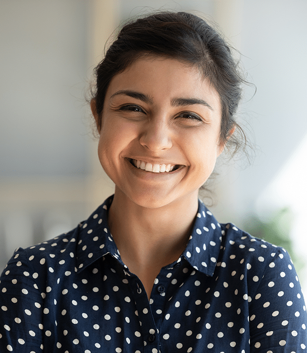 Smiling woman wearing navy polka dot shirt in bright indoor clinical setting.